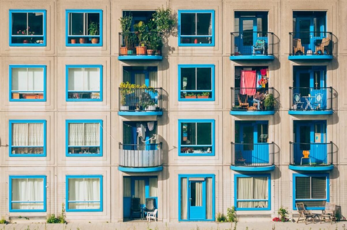 İzale-i şuyu — mavi pencereli, çiçekli balkonlu apartman cephesi